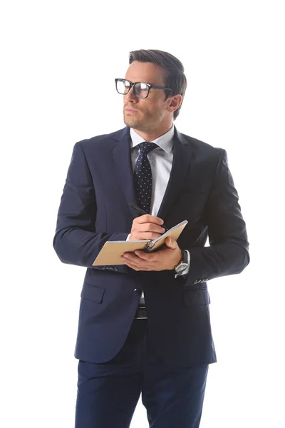 Empresário sério em óculos escrevendo em livro didático isolado em fundo branco — Fotografia de Stock