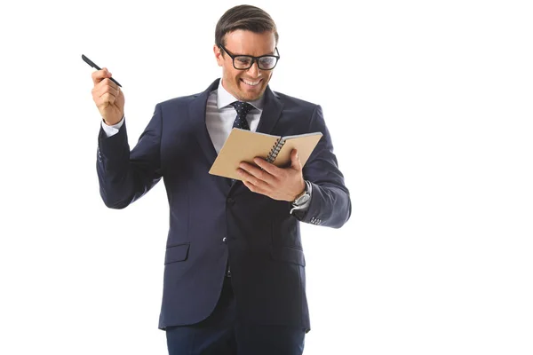 Feliz hombre de negocios en gafas haciendo gesto de idea por pluma y sosteniendo libro de texto aislado sobre fondo blanco - foto de stock