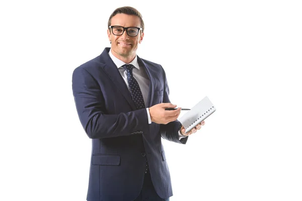 Homem de negócios sorridente em óculos apontando por caneta em livro didático isolado em fundo branco — Fotografia de Stock