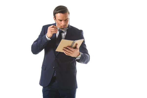 Hombre de negocios enfocado en ponerse anteojos y mirar libro de texto aislado sobre fondo blanco - foto de stock