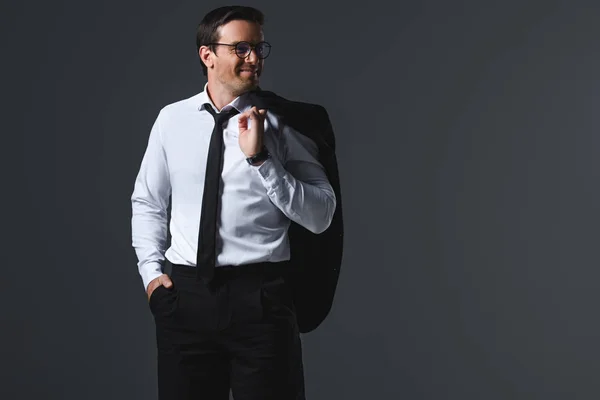 Homme d'affaires souriant en lunettes tenant veste sur l'épaule isolé sur fond gris — Photo de stock