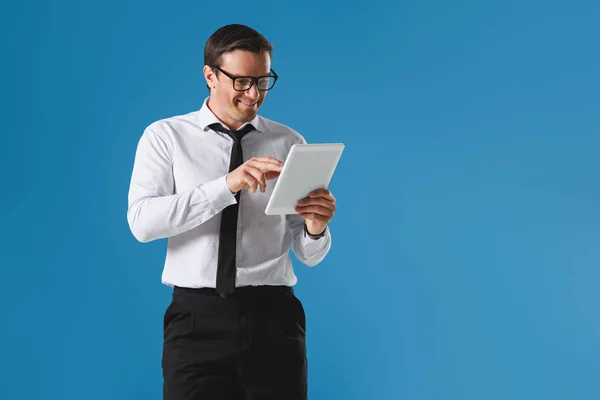 Schöner lächelnder Geschäftsmann mit Brille und digitalem Tablet isoliert auf blauem Grund — Stockfoto