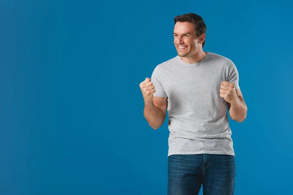 Happy man shaking fists and looking away isolated on blue — Stock Photo