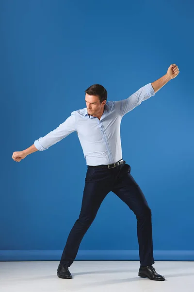 Full length view of handsome man posing and looking away on blue — Stock Photo