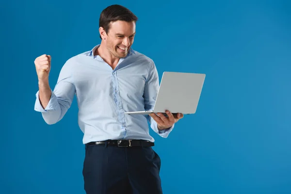 Веселый красавец, держащий ноутбук в изоляции на голубом фоне — стоковое фото