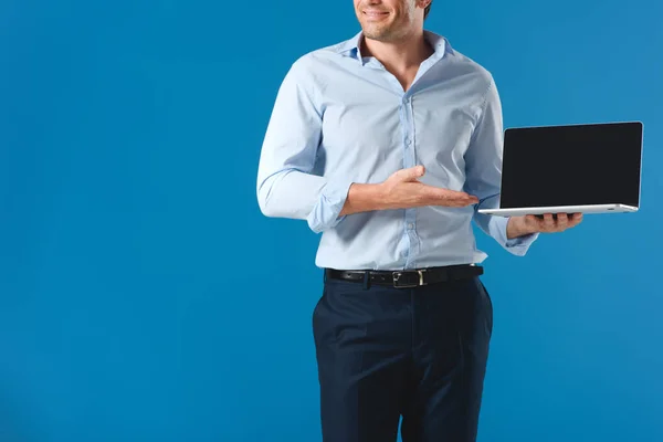 Recortado disparo de sonriente hombre sosteniendo portátil con pantalla en blanco aislado en azul - foto de stock