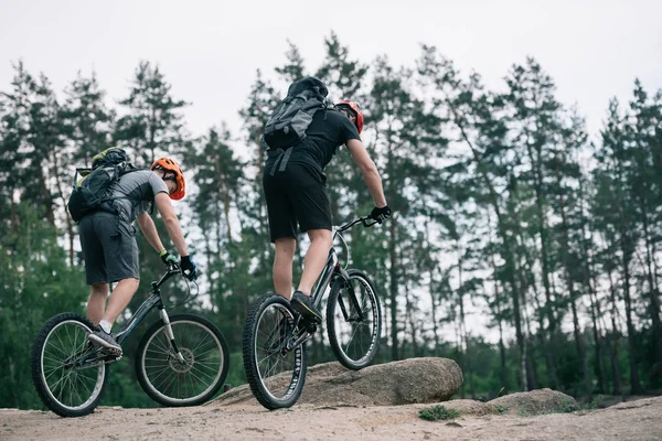 Два чоловічі екстремальні велосипедисти в захисних шоломах катаються на гірських велосипедах у лісі — стокове фото