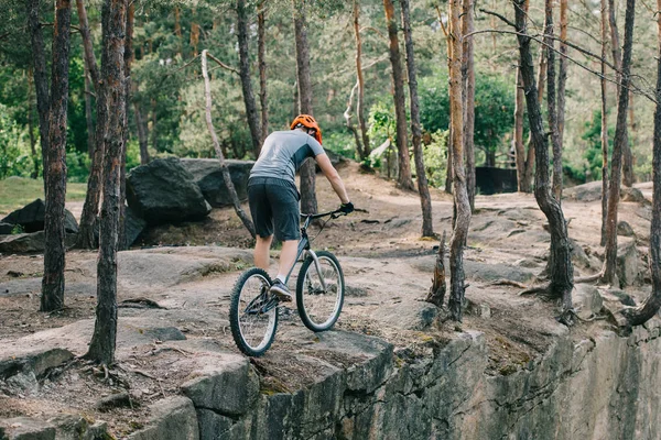 Rear view of male cyclist in helmet performing stunt on mountain bike — Stock Photo