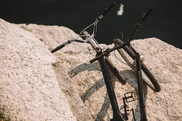 Enfoque selectivo de bicicletas de montaña en acantilado rocoso sobre el río - foto de stock