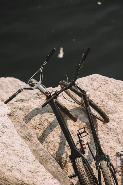 Підвищений вид на два гірські велосипеди на скелястій скелі над річкою — стокове фото