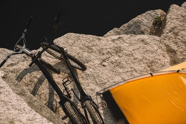 Erhöhte Sicht auf Mountainbikes und Touristenzelt auf felsiger Klippe über dem Fluss — Stockfoto