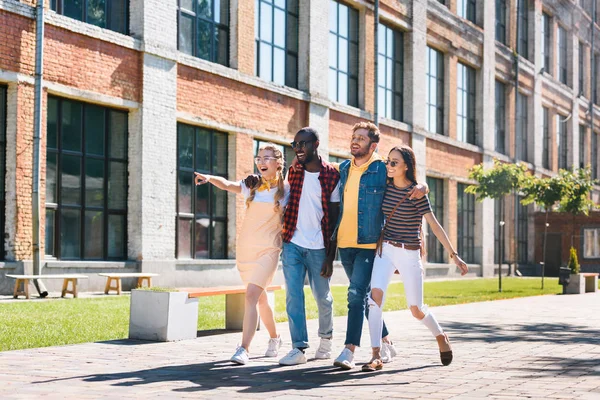 Felice gruppo multiculturale di amici che si abbracciano mentre camminano per strada insieme — Foto stock