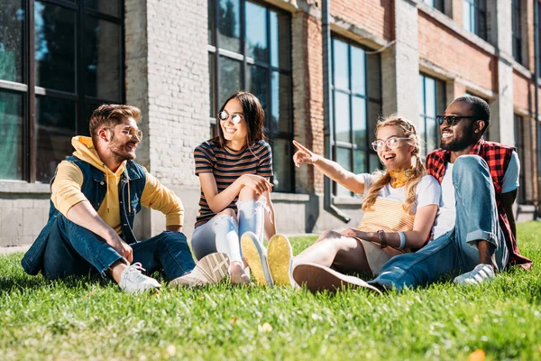 Multiethnic group of friends resting on green grass in city — Stock Photo