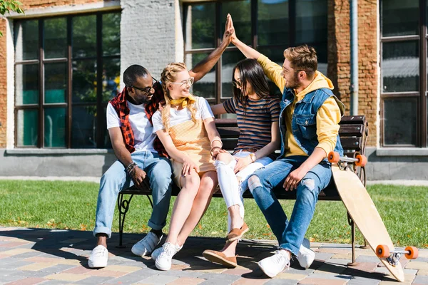 Multikulturelle Paare ruhen sich gemeinsam auf Bank auf der Straße aus — Stockfoto