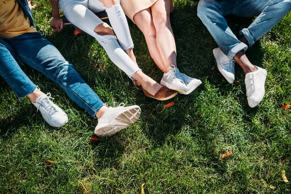 Cropped shot of multiethnic friends resting on green grass — Stock Photo