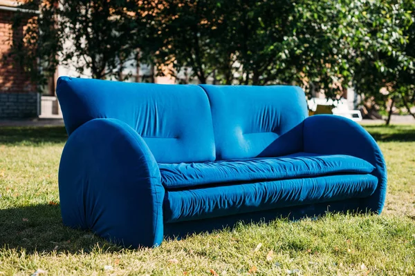 Close up vista de sofá azul de pé no gramado verde no parque — Fotografia de Stock