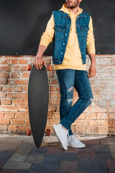 Cropped shot of man with longboard standing on street — Stock Photo