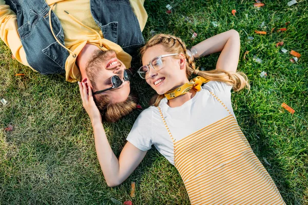 Overhead view young happy couple resting on green grass in park — Stock Photo