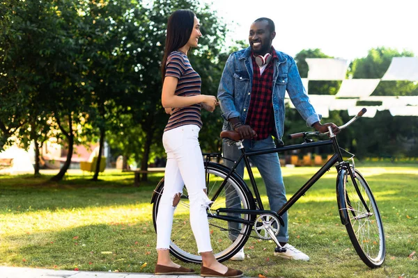 Smiling multiracial couple with retro bicycle having conversation in park — Stock Photo