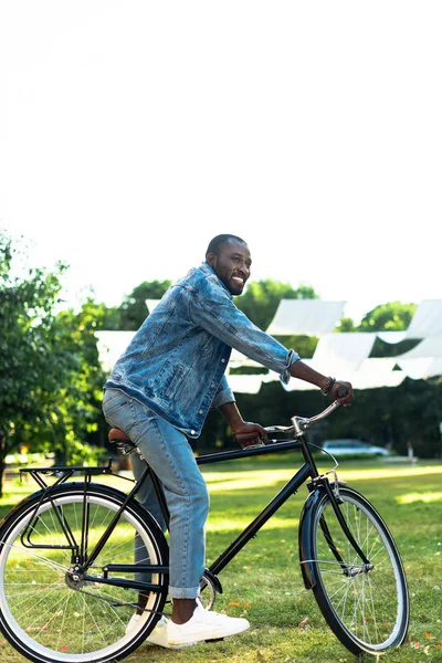 Smiling african american man riding retro bicycle in park — Stock Photo