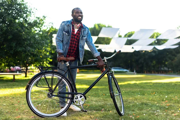 Sorridente uomo africano americano con bicicletta retrò nel parco — Foto stock