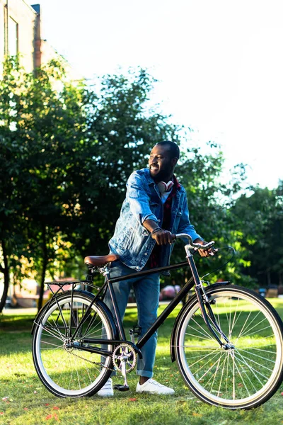 Sorridente afro-americano homem com retro bicicleta no parque — Fotografia de Stock