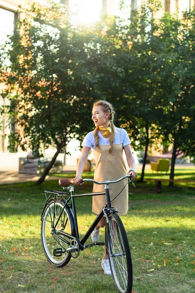 Giovane bella donna con bicicletta retrò nel parco — Foto stock