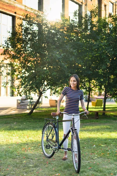 Joven asiático mujer con retro bicicleta en parque - foto de stock