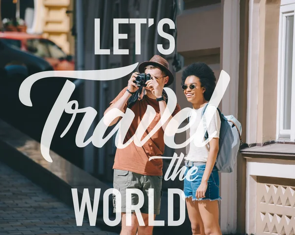 Male traveler taking picture on camera and african american girlfriend standing near. Inspiration - lets Travel the world — Stock Photo