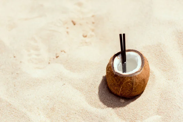 Foco seletivo de coquetel em casca de coco na praia arenosa — Fotografia de Stock