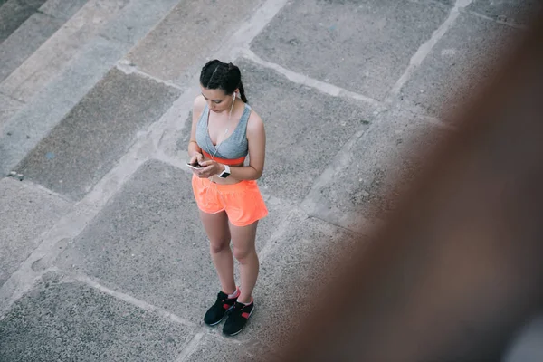 Visão aérea de jovem esportista usando smartphone — Fotografia de Stock