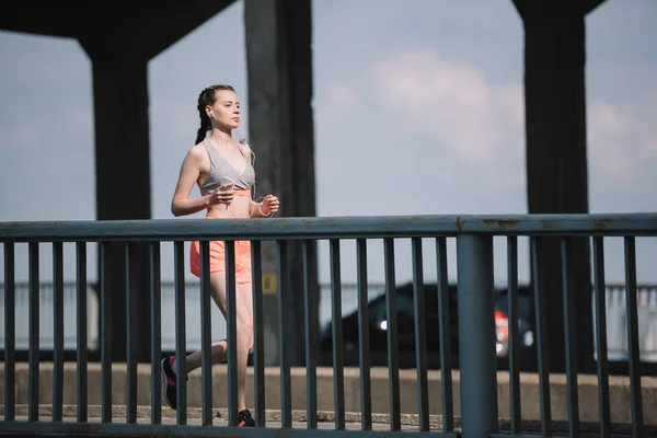 Joggeuse écouter de la musique et courir sur le pont en ville — Photo de stock