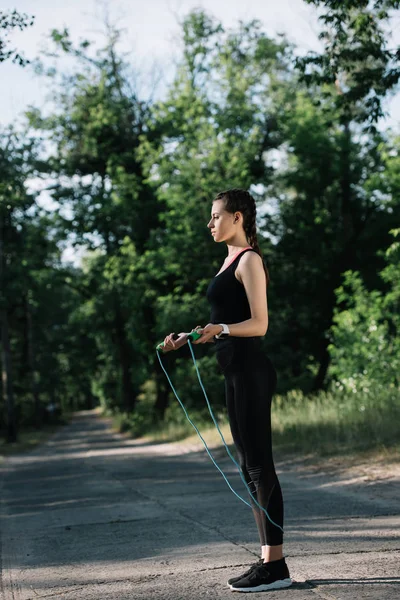 Спортсменка тренируется с скакалкой на дорожке в парке — стоковое фото