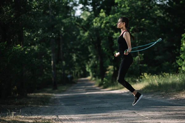 Treinamento esportivo atraente mulher com corda de salto no caminho no parque — Fotografia de Stock