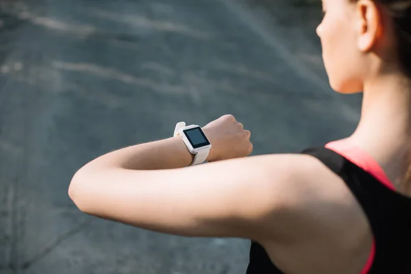 Cropped view of athletic woman looking at smart watch — Stock Photo