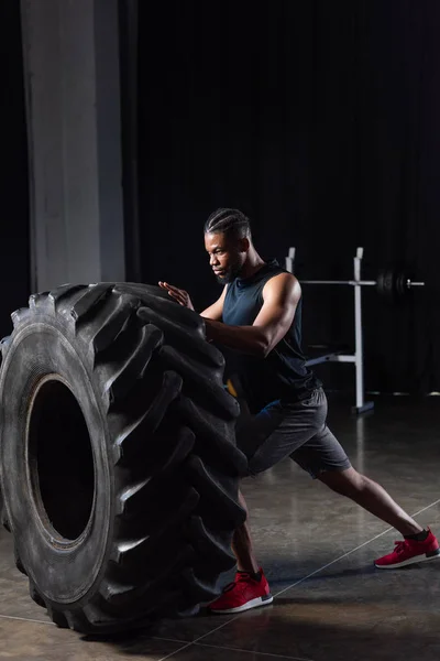 Вид сбоку на мускулистого молодого африканского спортсмена с шинами — стоковое фото