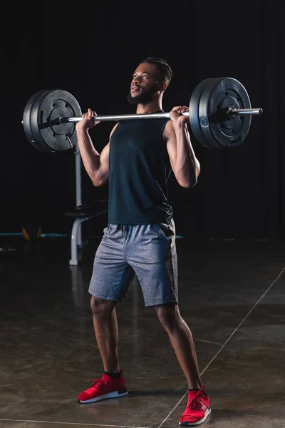 Athletic african american man in sportswear lifting barbell in gym — Stock Photo