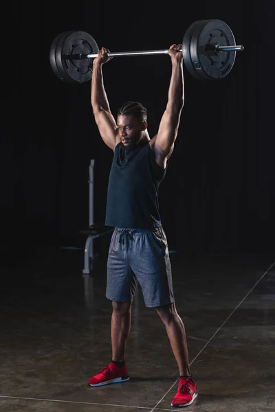 Ganzkörperansicht des muskulösen afrikanisch-amerikanischen Sportlers beim Heben der Langhantel im Fitnessstudio — Stockfoto