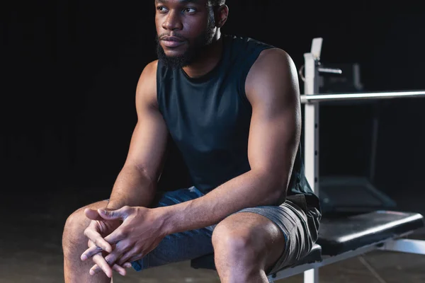 Cropped shot of young african american sportsman with talcum powder on hands sitting and looking away — Stock Photo