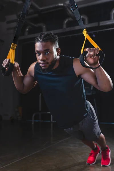 Joven deportista afroamericano enfocado que ejerce con bandas de resistencia - foto de stock