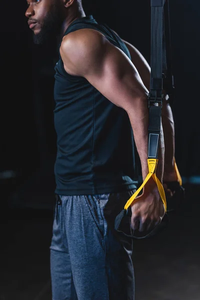 Cropped shot of muscular african american sportsman exercising with suspension straps — Stock Photo