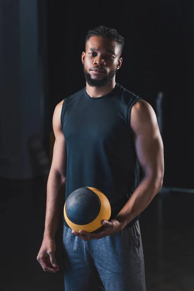 Schöner junger afrikanisch-amerikanischer Sportler, der Ball hält und in die Kamera schaut — Stockfoto