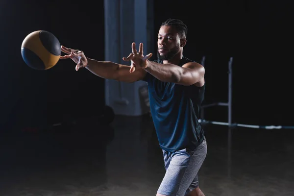 Musculoso afroamericano deportista entrenamiento con pelota en gimnasio - foto de stock