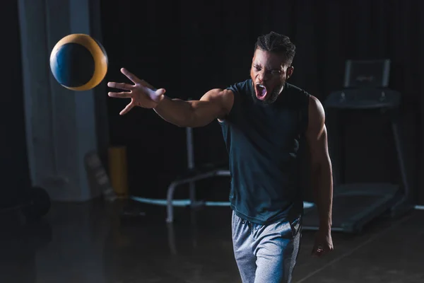 Emotionaler afrikanisch-amerikanischer Sportler trainiert mit Ball im Fitnessstudio — Stockfoto