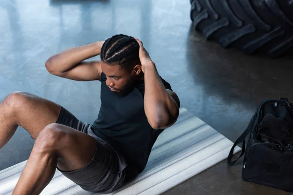 Vista de ángulo alto del hombre afroamericano muscular haciendo abdominales en el gimnasio - foto de stock