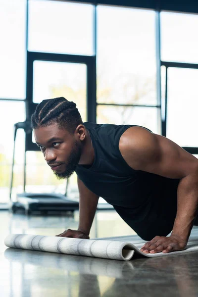 Enfocado muscular afroamericano hombre haciendo flexiones en gimnasio - foto de stock