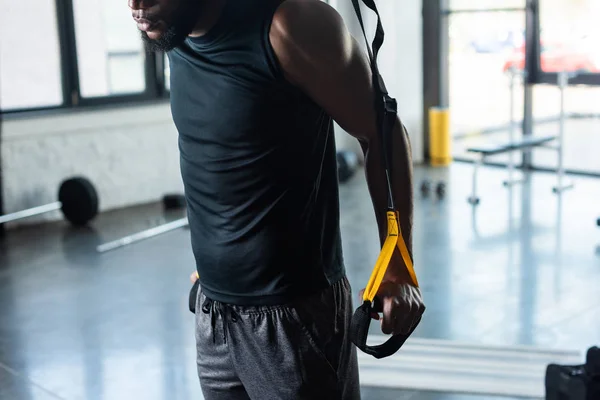 Schnappschuss eines muskulösen jungen Afroamerikaners beim Training mit Fitnessbändern im Fitnessstudio — Stockfoto