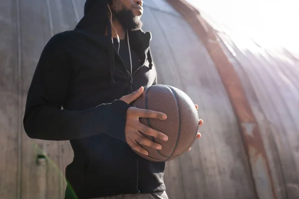 Colpo ritagliato di uomo africano americano in possesso di pallone da basket sulla strada — Foto stock