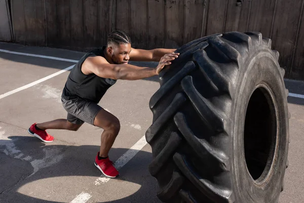 Visão de alto ângulo do atlético afro-americano exercitando com pneu na rua — Fotografia de Stock