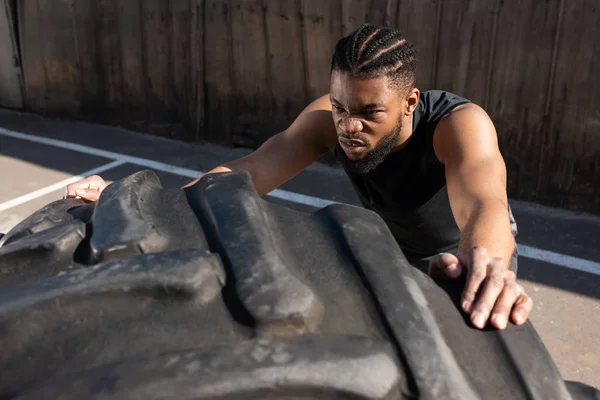 Visão de alto ângulo de esportivo Africano americano homem formação com pneu na rua — Fotografia de Stock